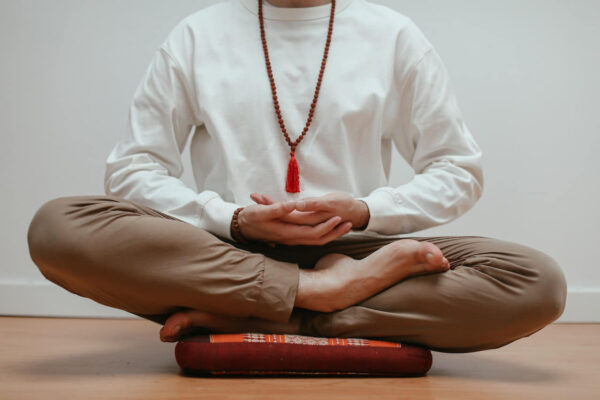 Mann sitzend auf Meditationskissen